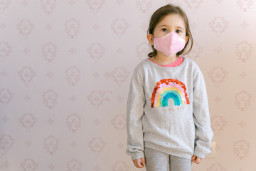 baby in a pink mask on a background of a pink wall. portrait of a 5 years old girl posing in front of the camera