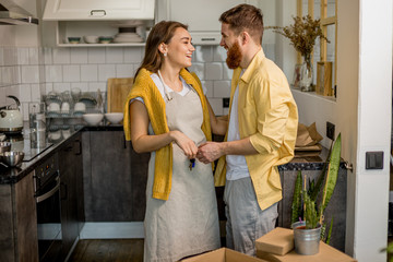 portrait of young happy couple moving in new home, caucasian married couple stand in the kitchen next to packed boxes. family, flat, house, apartment, mortgage concept