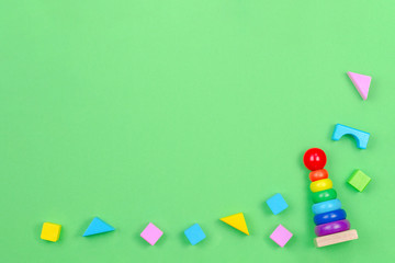 Kids toys background frame with baby stacking rings pyramid and colorful blocks on green background