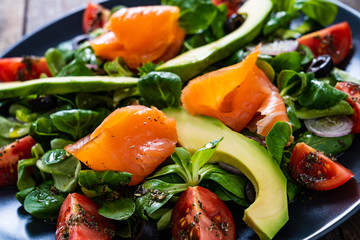 Salmon salad - smoked salmon and vegetables on wooden background
