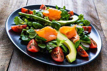 Salmon salad - smoked salmon and vegetables on wooden background
