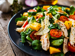Caesar salad - fried chicken breast and vegetables on wooden table
