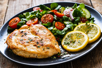 Pork chop with lemon and vegetable salad on wooden background

