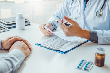 Doctors and patients sit and talk to the patient about medication. At the table near the window in...