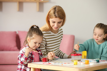 Fototapeta premium Mother and daughters painting at table indoors. Playing with children