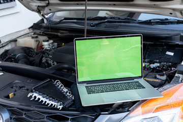 Laptop computer on car hood for engine diagnostic. Car garage repair service concept.