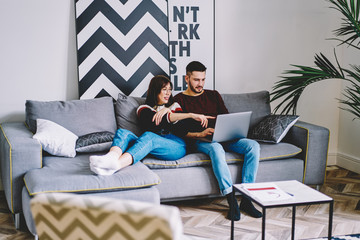 Positing female in casual wear ponting on laptop computer screen watching movie with boyfriend on...