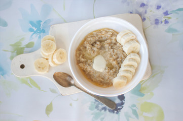 Oats porridge with banana slices in light background.