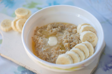 Oats porridge with banana slices in light background.