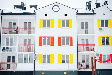 facade of a residential building with windows with multi-colored shutters, front view