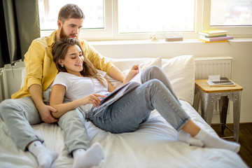 young caucasian married couple relax at home, enjoy being together, have rest lying on bed and...