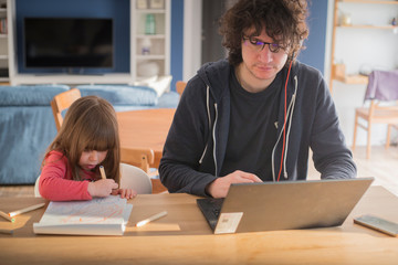 Young father working from home with little daughter drawing during covid-19 lockdown. Child drawing...