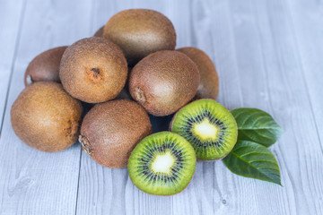 a bunch of fresh ripe kiwis on the table close-up. whole kiwi fruit and half a kiwi on the wooden...