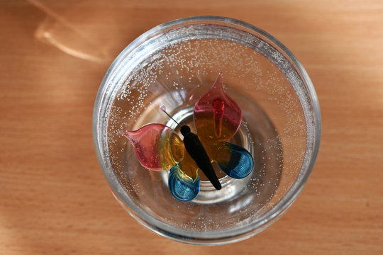 glass multi-colored butterfly in a cup with water