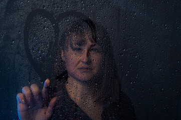 Beautiful girl behind wet glass