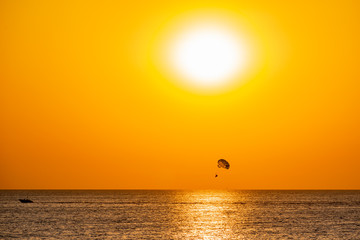 Silhouette of a parachute and a skydiver against the background of a bright burning sunset over the...