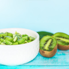 slices of sliced kiwi in a white bowl close-up. kiwi slices and kiwi halves on the table.