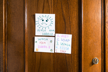 Drawings by a child of positive messages for the coronavirus hanging on the bathroom door. Wash your hands.