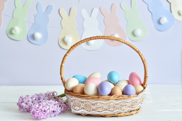 Naklejka na ściany i meble Colorful easter eggs in basket on pastel color background with flowers, copy space.Easter decorations. Easter background with painted eggs with Hyacinth, top view. Spring greeting card
