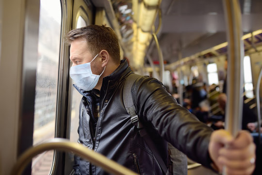 Mature man wearing disposable medical face mask in car of the subway in New York during coronavirus outbreak.