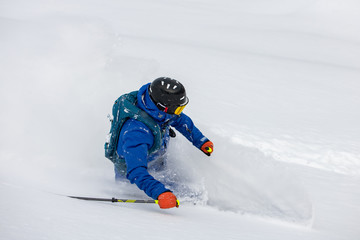 Fototapeta na wymiar Freeride skier rides over off-piste slope in snow capped forest. Skier enjoying a deep powder turn.