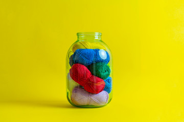 some yarn rolls of different color put inside the glass bank at home, creative storage sollution