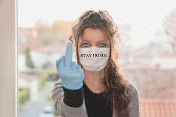 young woman wearing surgical mask and gloves is making obscene gesture 