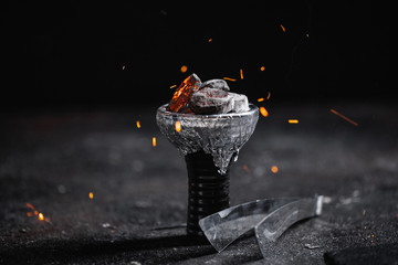 Closeup of a ceramic hookah or waterpipe head with alufoil or thin foil, sparkling hot coal