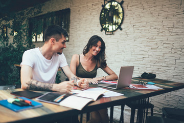 Cheerful coworking friends watching video on laptop