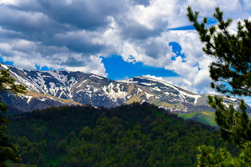 Beautiful mountain panorama with lush greens, blue skies, and puffy clouds