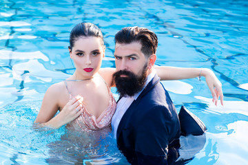Couple relaxing in swimming pool in fashion dress. Travel vacation. Relaxation concept. Sexy couple...
