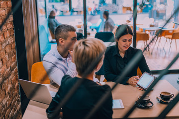 Business meeting with young couple and their financial advisor inside a cafe with the focus through a fence.