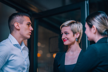 Group of three young entrepreneurs discussing business ideas in front of an office.