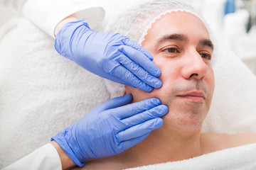 Cosmetology massage of male face with two hands