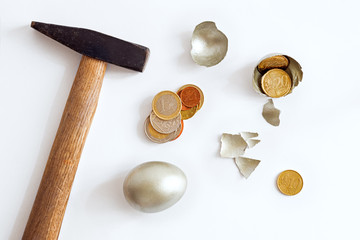 broken golden egg, shell, hammer and coins on a white background, crisis concept, last money,