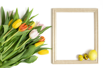 Easter frame with a bouquet of tulip flowers and yellow eggs on a white background. Copy space, top view.