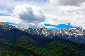 Beautiful mountain panorama with lush greens, blue skies, and puffy clouds