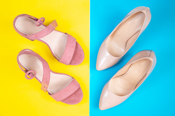 Women's pink summer sandals and pumps on a yellow and blue background. Fashionable shoes for young girls. Top view.