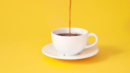 Female hand pours fragrant strong coffee into a white ceramic cup on a yellow table. Hot drink and aluminum metal cezve - Powered by Adobe
