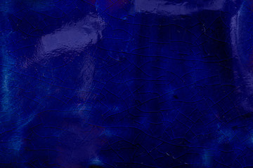 cracks on glazed ceramics, dark blue color, background, close-up. 