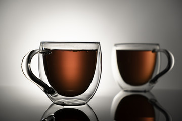 Two glass mugs with tea on a white background