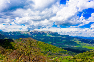 Beautiful mountain panorama with lush greens, blue skies, and puffy clouds