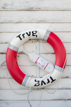 AALESUND, NORWAY - 2017 APRIL 27. Tryg red lifebuoy on a old grunge wooden plank wall