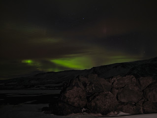 Sterne und grüne Polarlichter über den Wolken