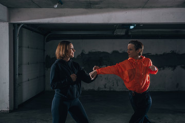 Two female athletes showing technical skills while practicing fighting in a garage