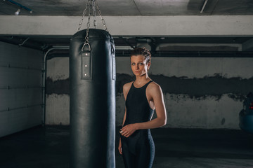 Young sportswoman doing high kick during boxing exercise in a garage.