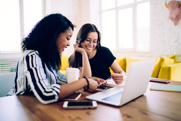 Amusing black woman looking cards with colleague at table