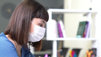 A young woman with mask is working from home with computer because of coronavirus spread impact.  - Powered by Adobe