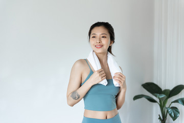 Fototapeta na wymiar A young Asian woman wipes sweat with a towel in front of a pure white background