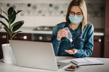 Coronavirus. Sanitizer gel. Business woman working, wearing protective mask in quarantine. Cleaning...